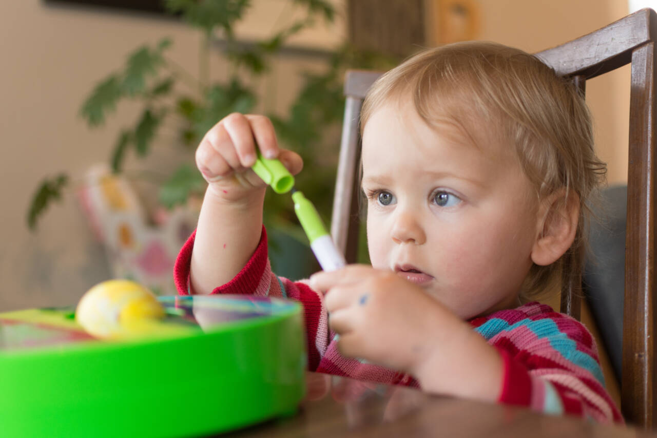 Toddler puts the cap back on a marker while doing an Easter egg craft; DIY arts and crafts with kids